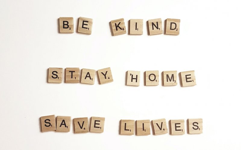 Scrabble pieces spelling out "Be Kind, Stay Home, Save Lives"