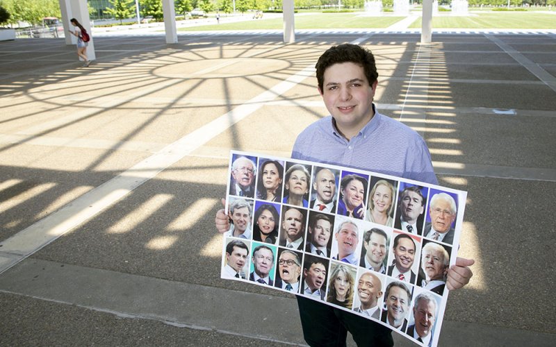 Public Administration grad student Austin Ostro holds up images of 24 Democrats vying to become the next president of the Unites States. 