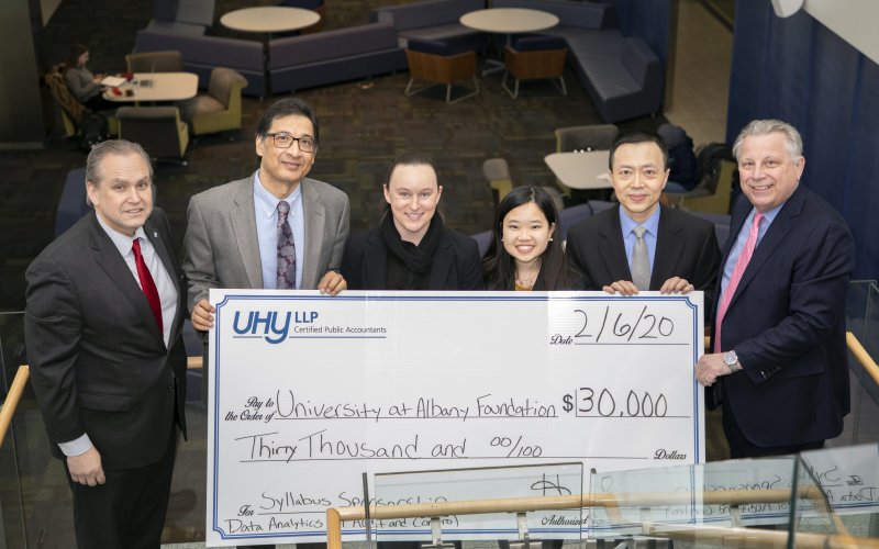 School of Business faculty and staff pose with a check and representatives from UHY