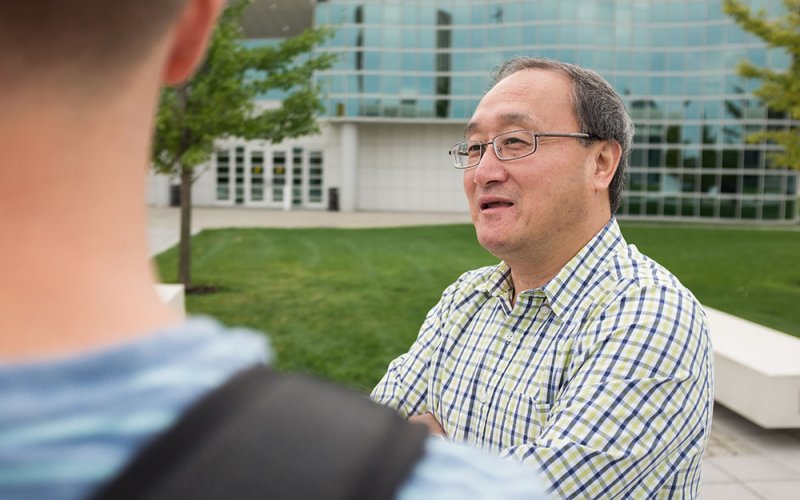 Professor Li Niu speaks with his students outside on the uptown campus.