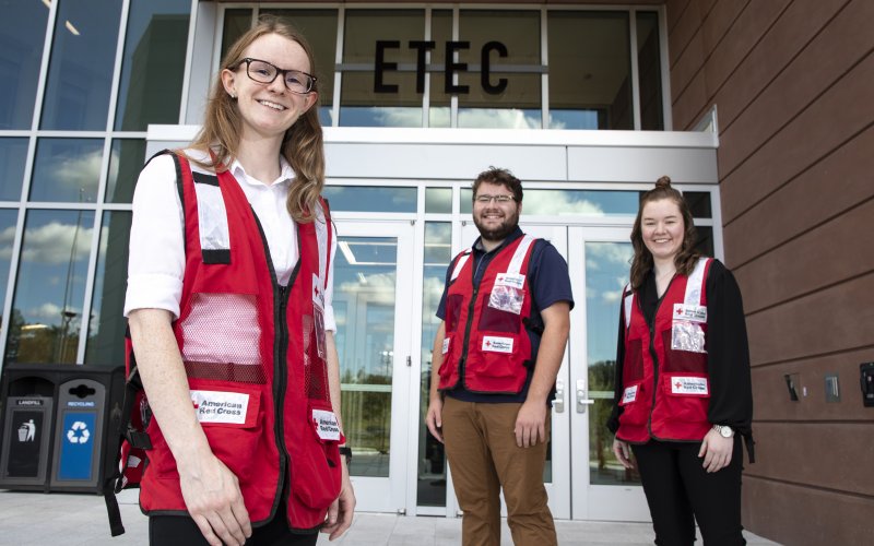 Nancy Kreis, Mike Clahane and Erin Golden stand in front of the ETEC building in American Red Cross vests.