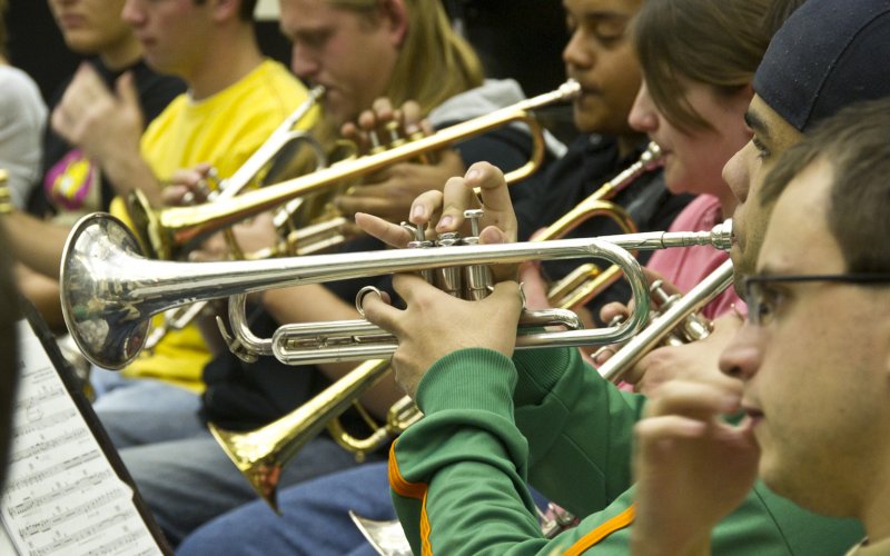 close up picture of five students playing trumpets