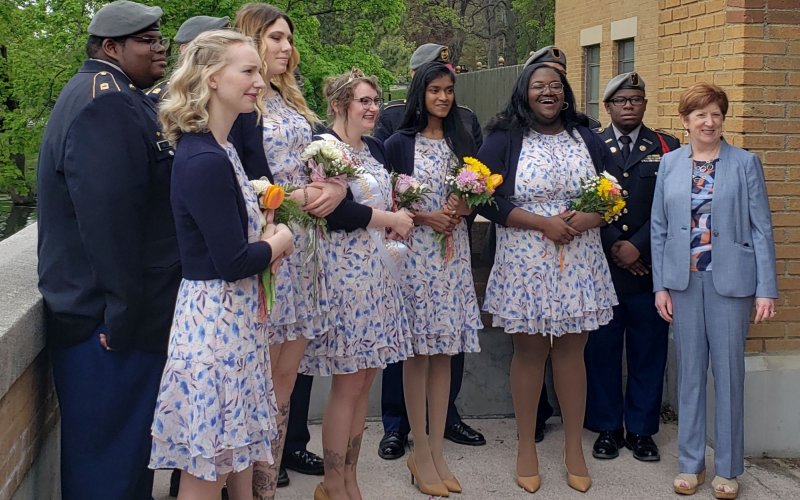 Members of the Albany Tulip Court, in matching white and blue dresses, hold flowers as they stand with Albany Mayor Kathy Sheehan.