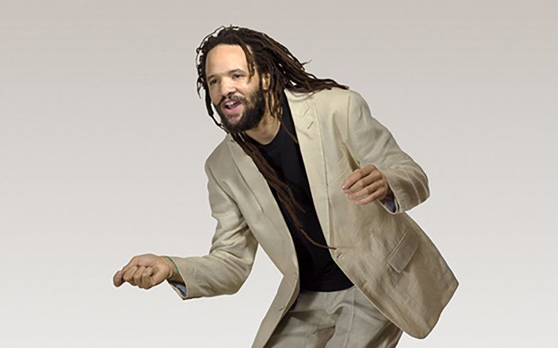 man with dreadlocks bending forward and snapping fingers