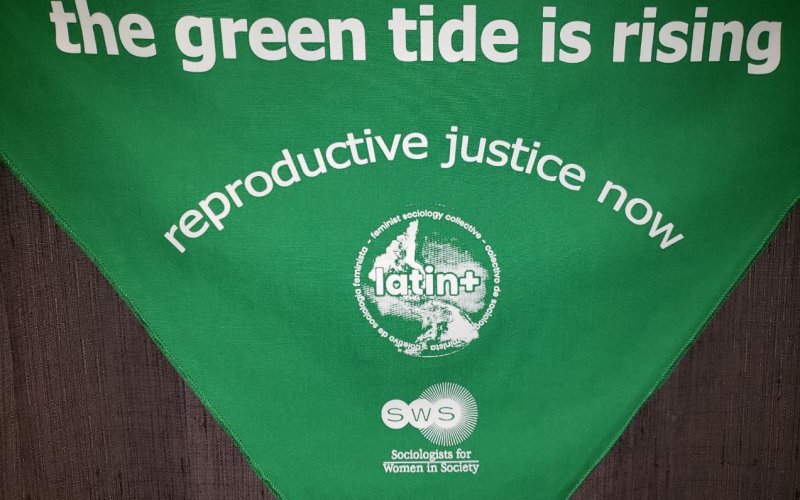 Green flag with text saying Green Tide Reproductive Justice Now on it