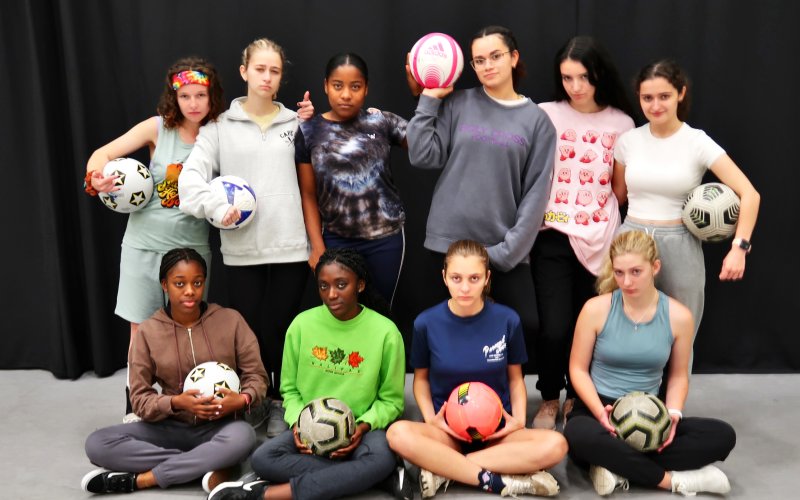 10 girls in two lines holding soccer balls
