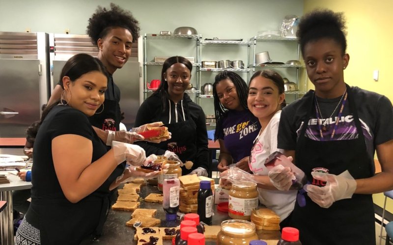 Six UAlbany students prepare peanut butter and jelly sandwiches in a Hannaford supermarket community kitchen as part of a community service day. 