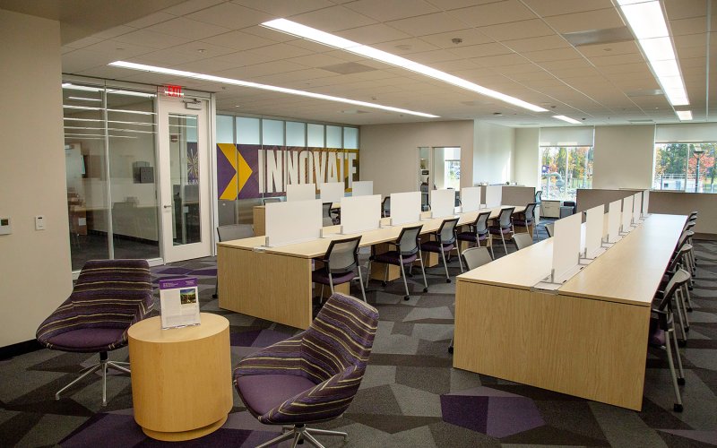 An indoor office with rows of tables and chairs with a large sign that says Innovate on the back wall.