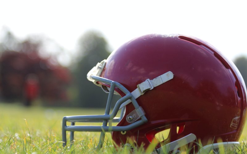A red football helmet sits on a grassy field. 