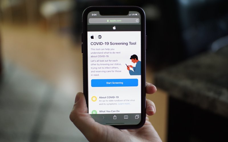 Person holds up phone with COVID-19 Screening Tool app opened.