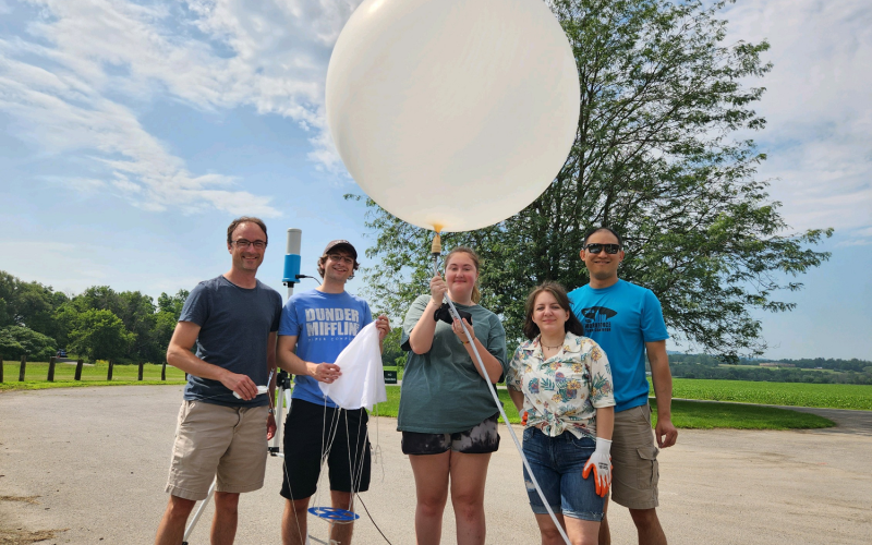UAlbany faculty and student researchers hold up a weather balloon that is ready to launch from the Schoharie Crossing State Historic Site.
