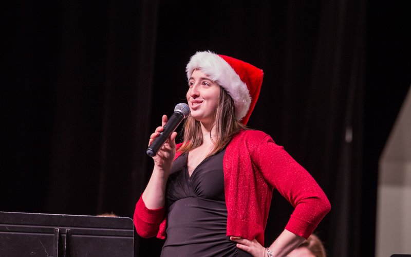 performer in santa hat and red sweater singing into microphone