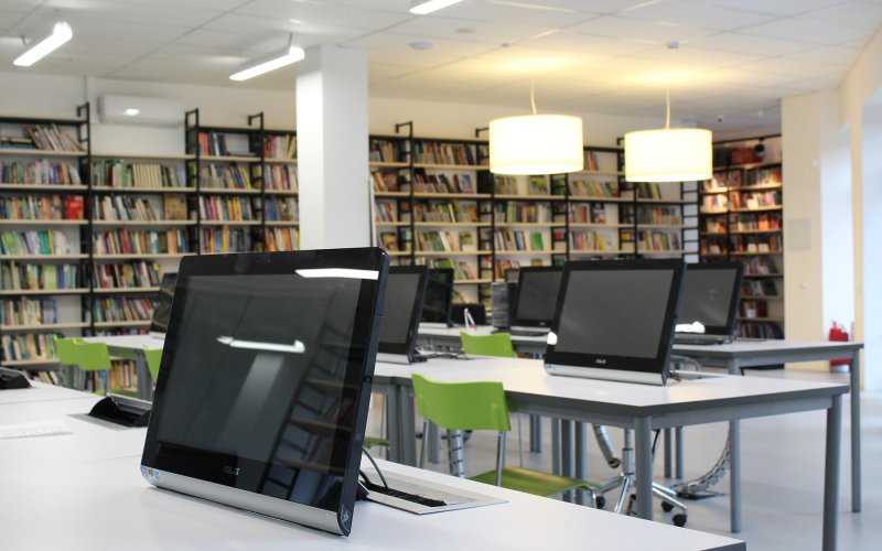 A library with rows of tablet computers at desks.