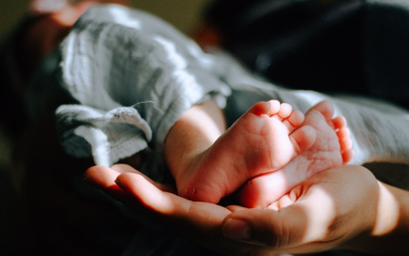 A baby's feet are held in an adult's hands. 