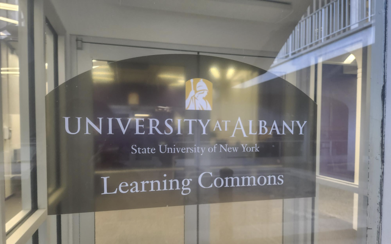 A glass door reads “University at Albany, State University of New York, Learning Commons”