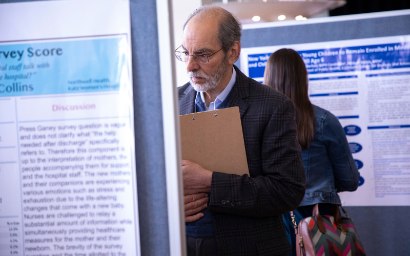 A professor reads a poster about student research.