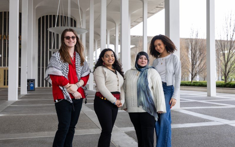 Four smiling students stand together on the Academic Podium