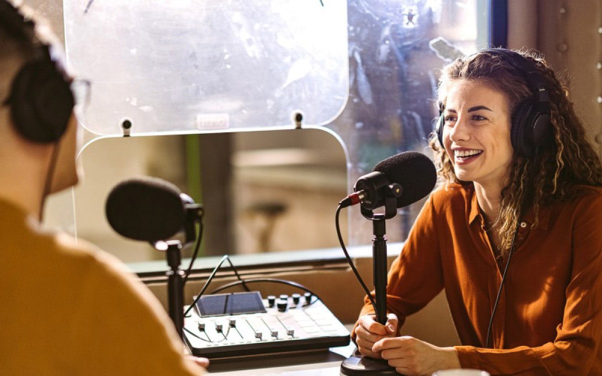 A podcast host interviews a guest in a recording studio.