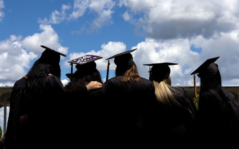 Students looking up at the sky in their caps and gowns