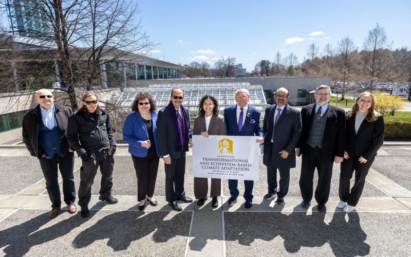Paul Tonko, UAlbany and community leaders stand in front of the UAlbany greenhouse holding up an ITECA sign.