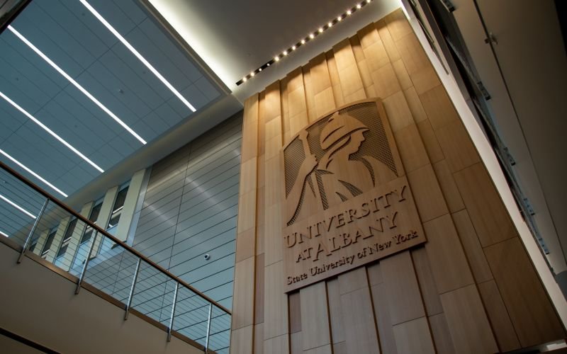 A building wall features and image of Minerva and the words "University at Albany State University of New York