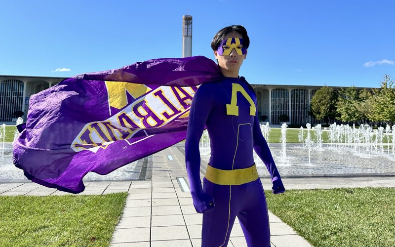 UAlbany Man stands in his purple and gold uniform at the University Entry Plaza.