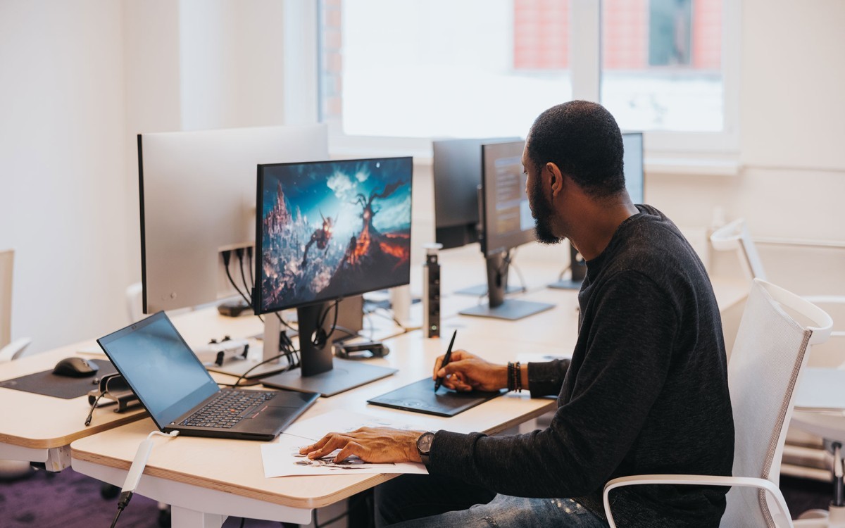 A game developer works on a new game’s visual design at his desk.