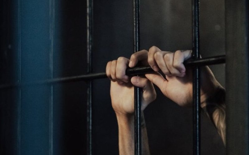 hands grasp prison bars