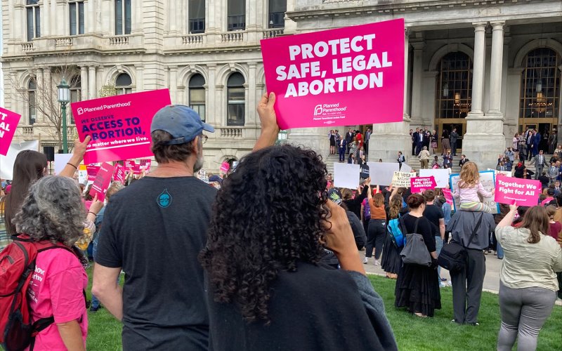 People holding up "protect Safe, Legal Abortion" and other signs at Abortion Rights rally outside the NYS Capitol building.