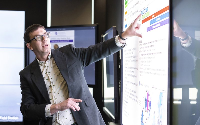 Nick Bassill points at a weather map in the xCITE lab.