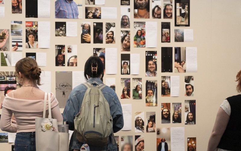 Visitors to the UAlbany Museum observe a series of photos and written works on a wall.