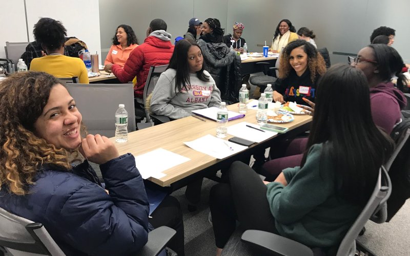 students sitting around tables smiling and talking