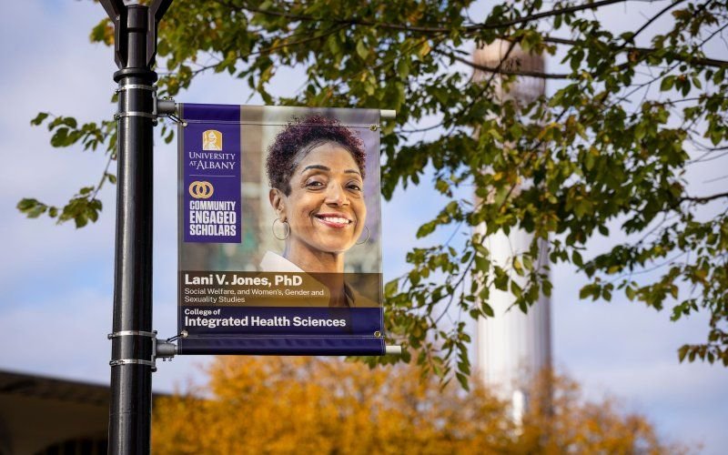 a banner on a post shows a smiling woman and the words University at Albany Community Engaged Scholars/ Lani V. Jones PhD/ College of Integrated Health Sciences