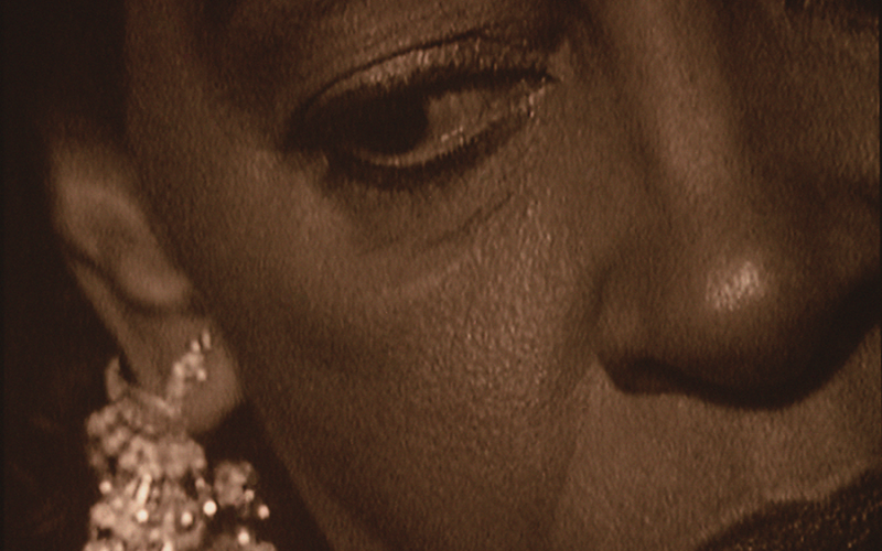 A close up of a person's face. Their eye and an intricate earring on their ear are visible.