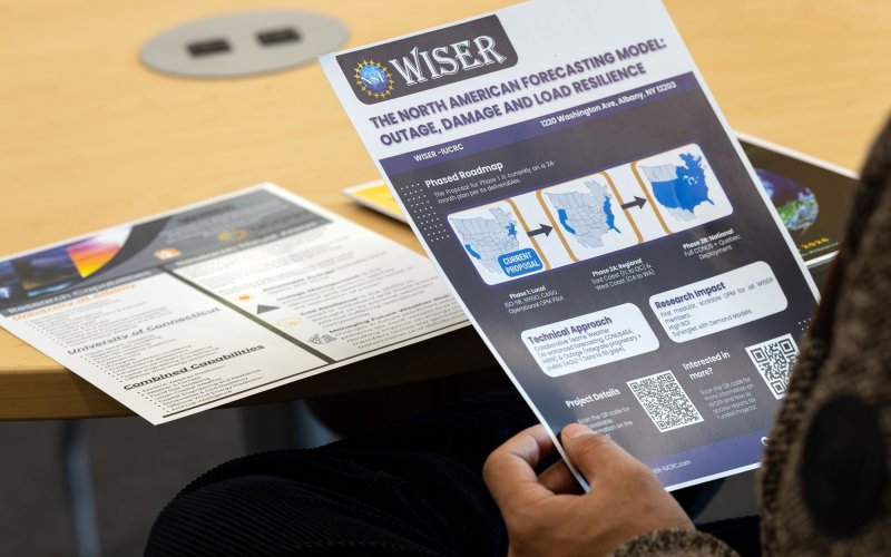 An attendee holds up the WISER North American Forecasting model one-pager at the WISER annual meeting. 