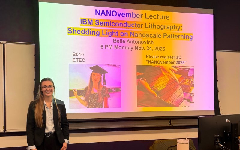 Belle Antonovich smiles in front of a big screen slide for her talk at UAlbany.