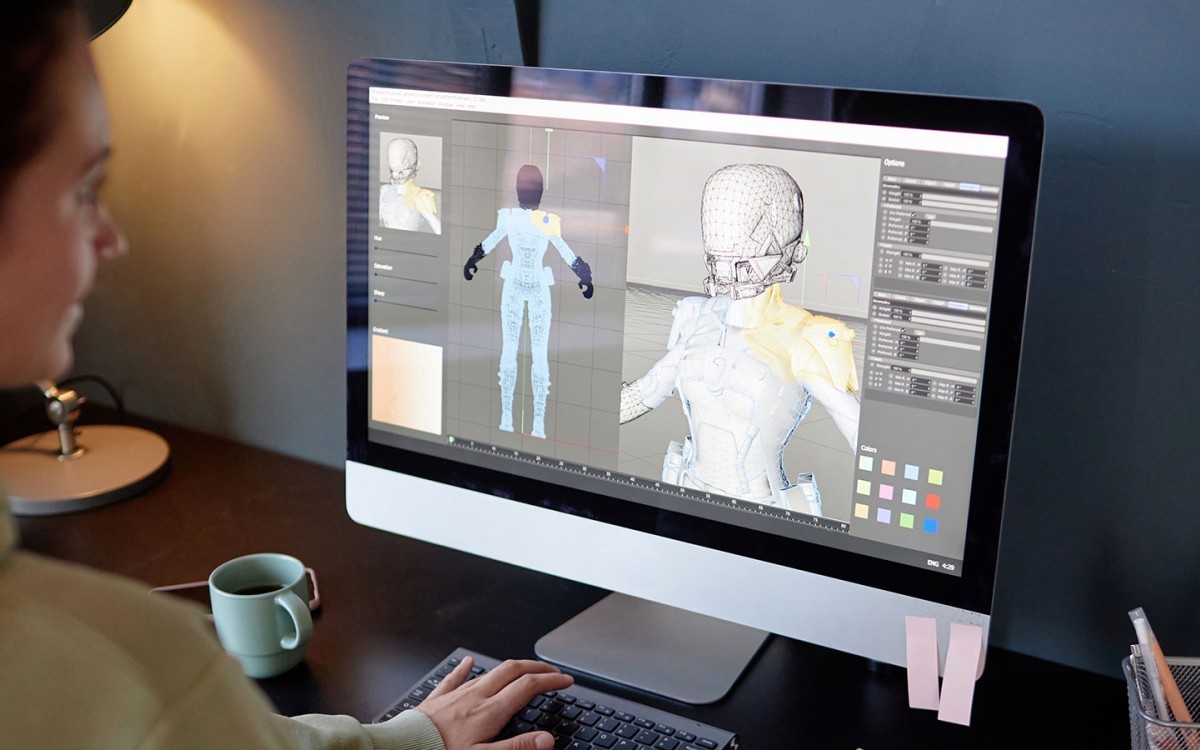 A game designer works on a character model on a computer.