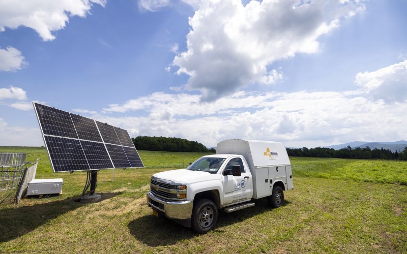 A New York State Mesonet truck parks in front of solar panels powering the network's Lake Placid site.