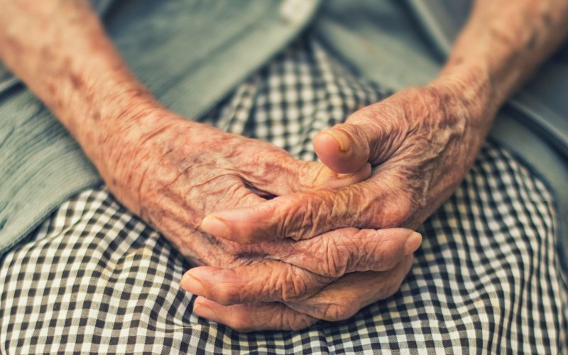 An older adults sits with her hands in her lap.