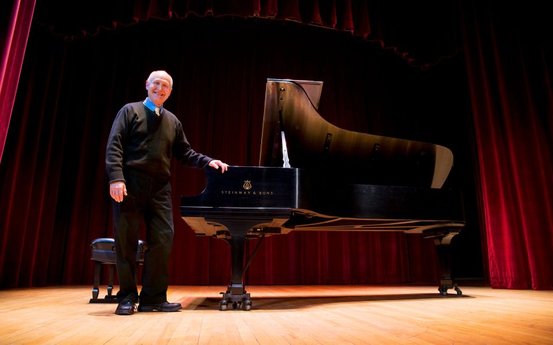 musician stands smiling by grand piano