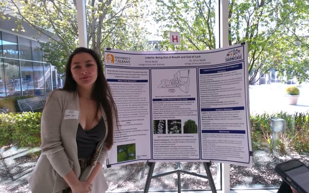 Anthropology major Anna Souls stands with her poster presentation at Showcase 2025.