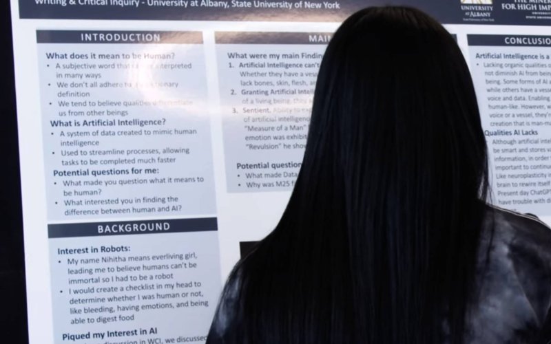 Undergraduate student stands in front of research poster from WCI AI & Writing Fair
