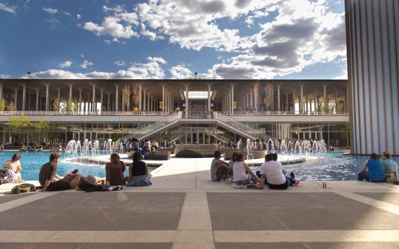 Students sit in the shadow of the carillon and put their feet in the Main Fountain's waters during a bright and beautiful summer day at UAlbany.