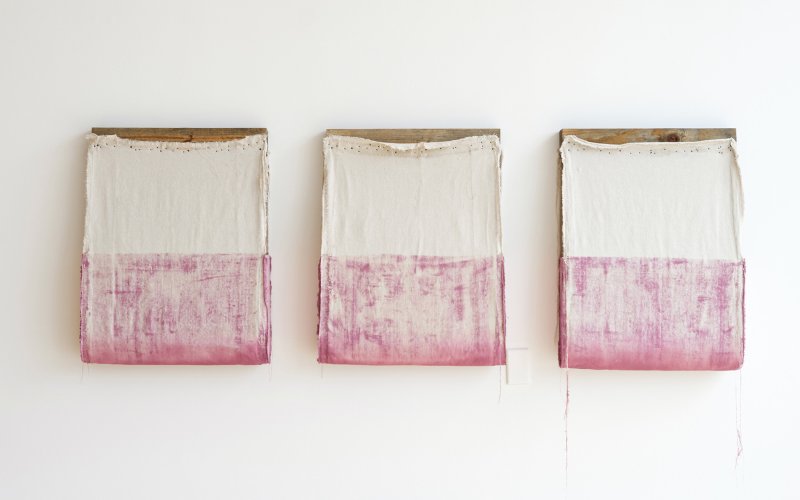 Burlap stapled to wood planks with magenta paint on the lower half
