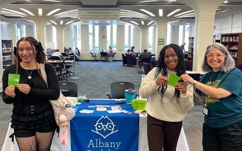 Students hold up their new Albany Public Library cards at University Library