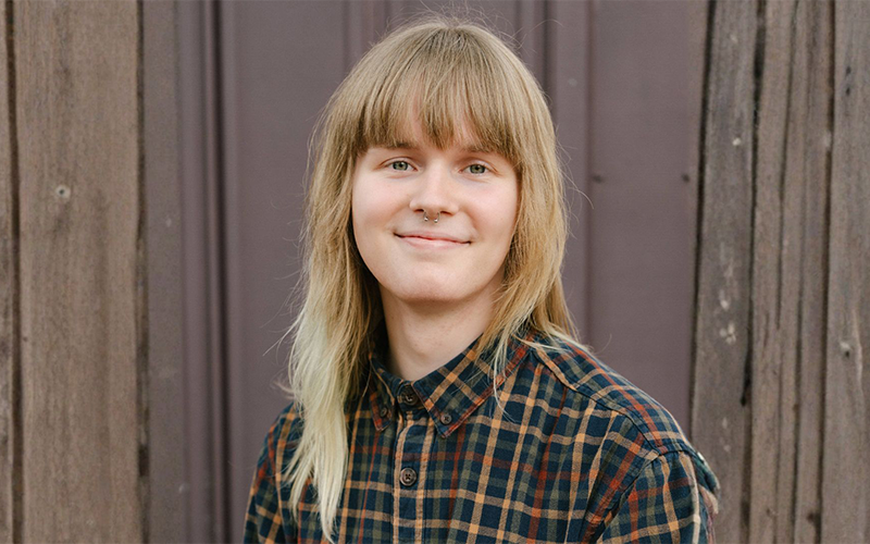 Portrait of a smiling Clark Mattoon standing in front of a wooden fence.