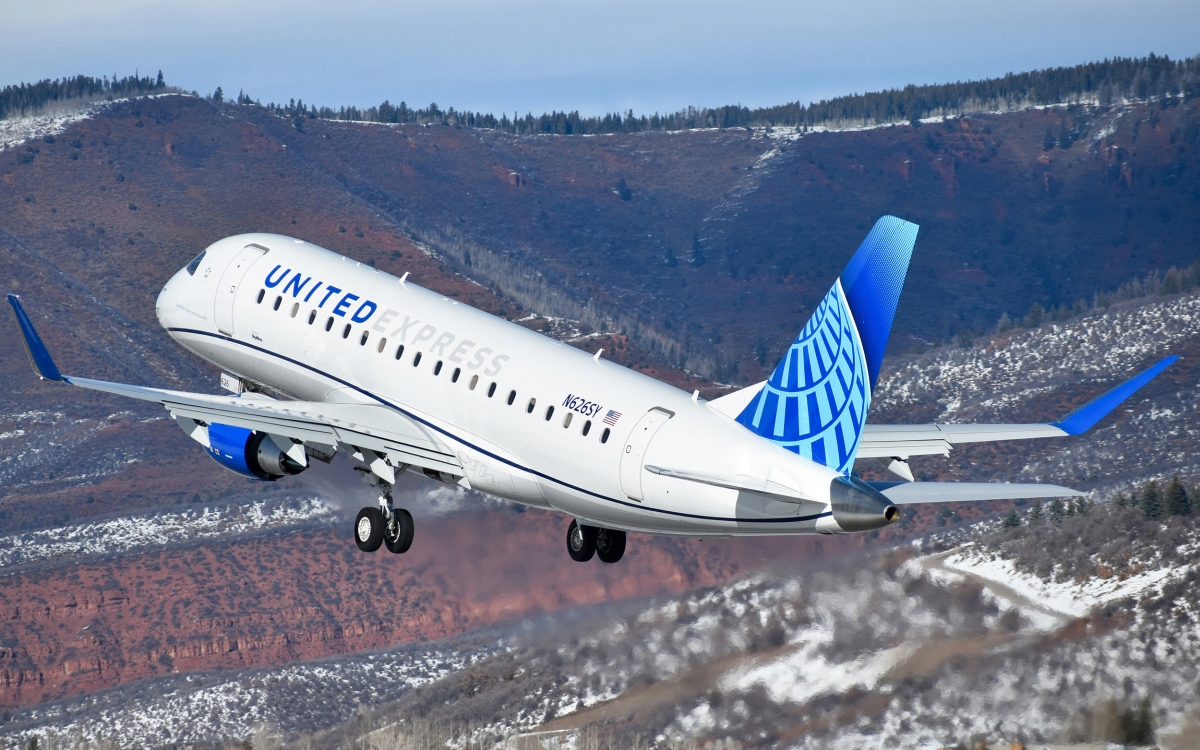 A jet labeled "United Express" flies over mountains.