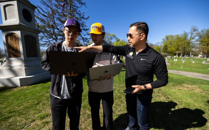 Students Weiming Lan and Micah Wang stand with professor Rui Li at the site of the Civil War memorial at Albany Rural Cemetary in Menands, N.Y.