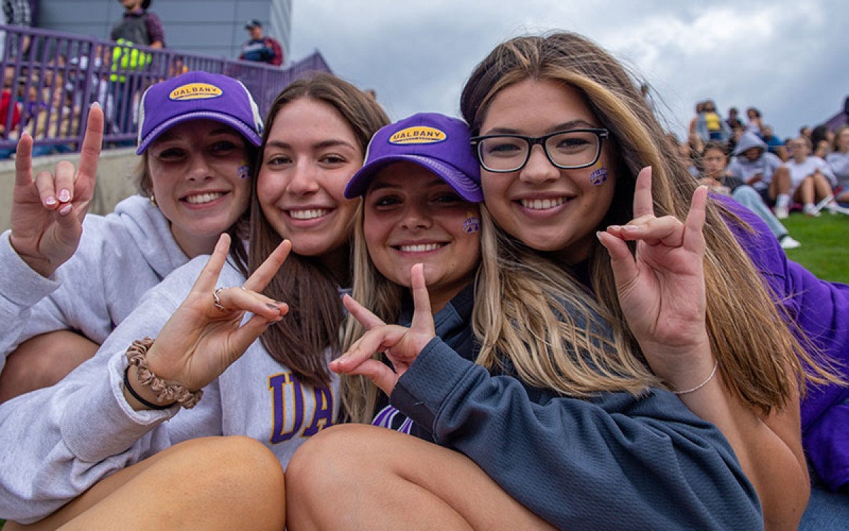 Four students making a Damien hand sign.