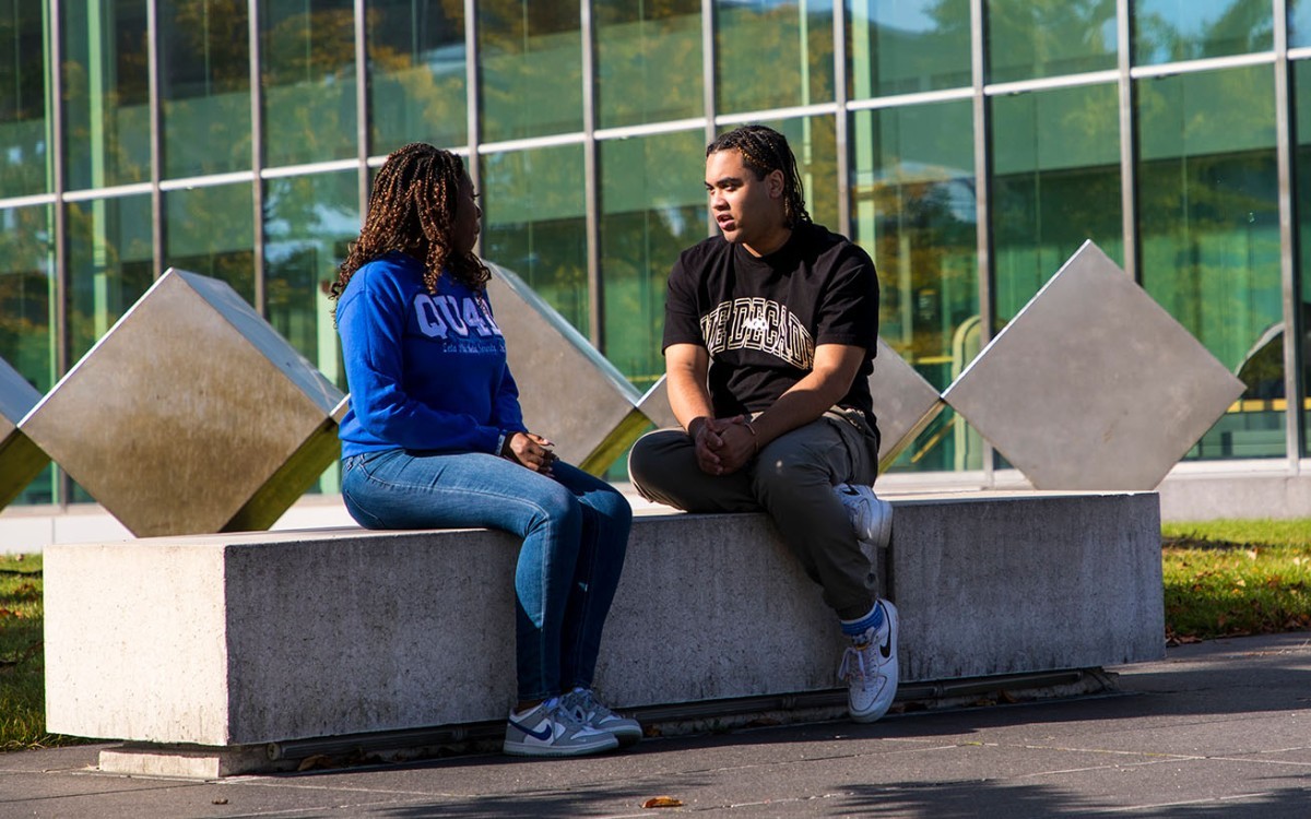 two student sitting on a bench near the massry building